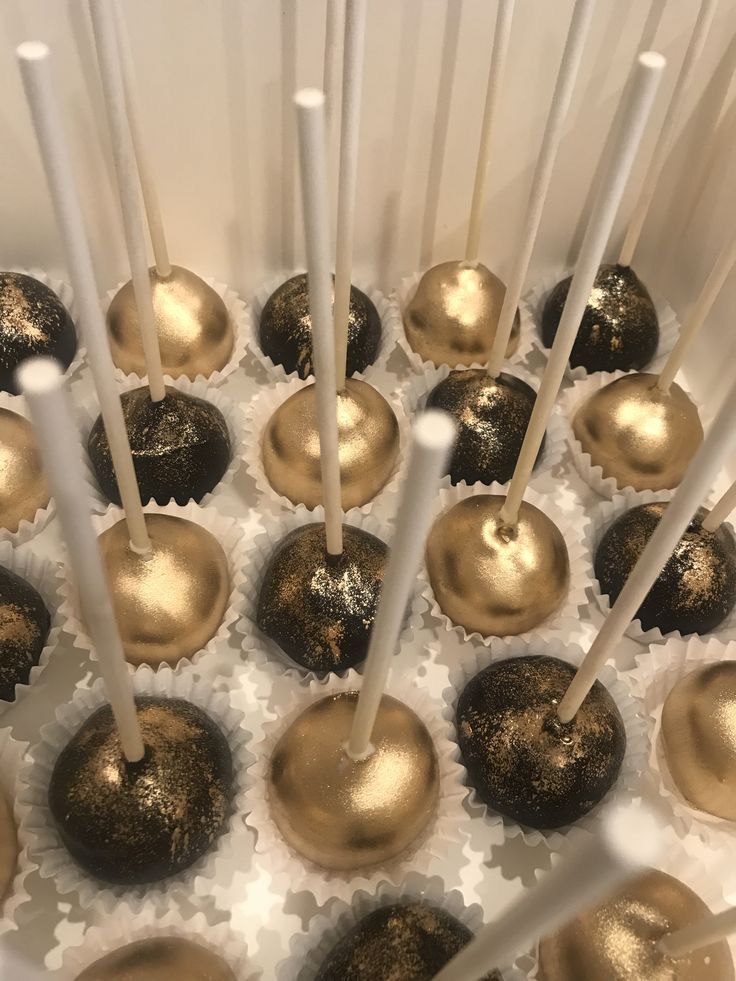 there are many chocolates with gold decorations on the top and white sticks sticking out of them