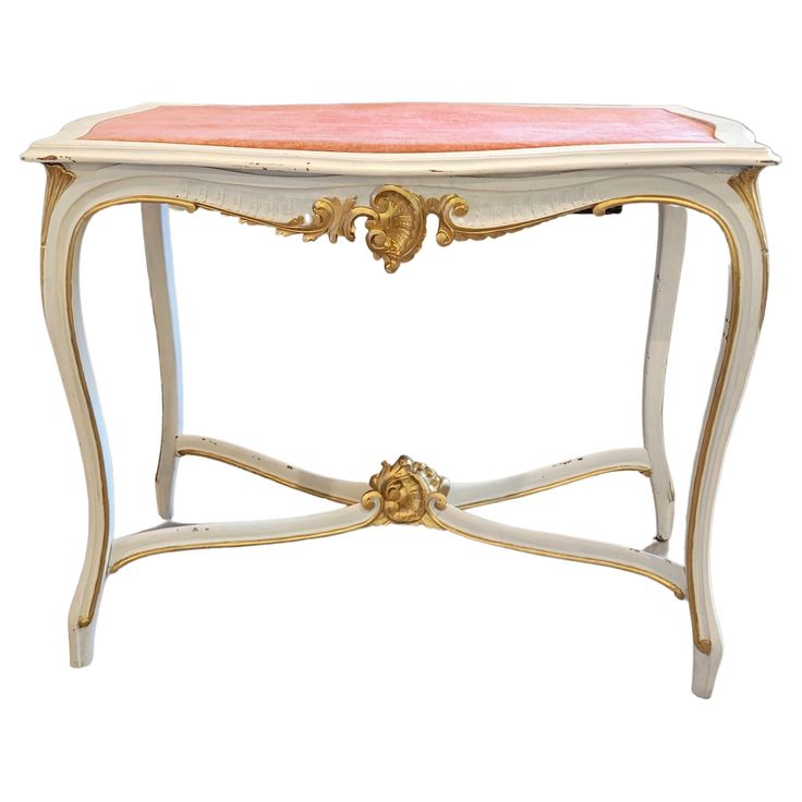 an antique console table with pink and white paint on the top, gold trimmings