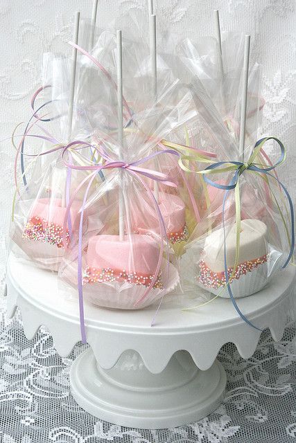 some pink and white cupcakes wrapped in clear cellophane on a cake plate