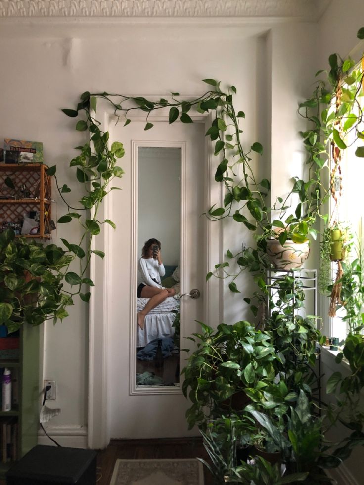 a woman sitting on a chair in front of a door surrounded by potted plants