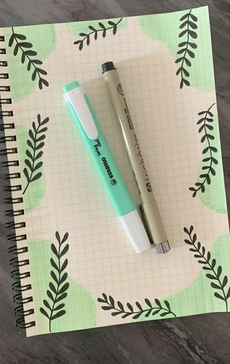 a pen sitting on top of a notebook next to a green and white flower pattern