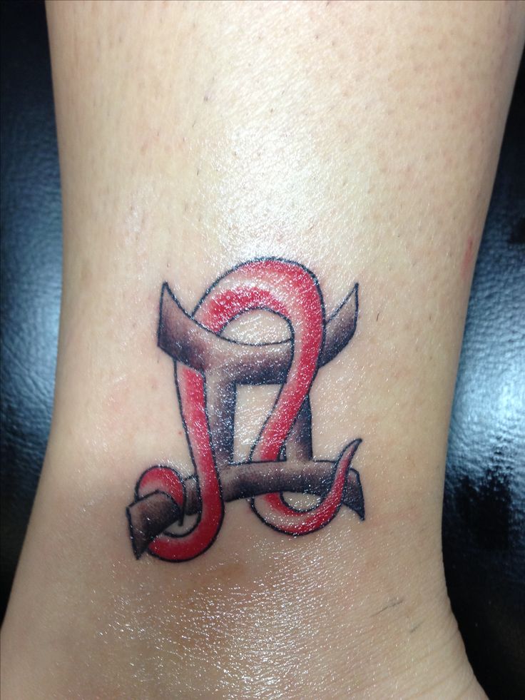 a small tattoo on the side of a woman's leg that has an anchor and two letters