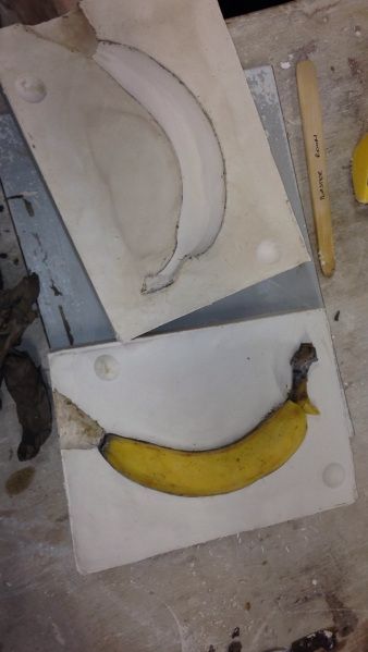 a banana sitting on top of a cutting board next to a knife and some other tools