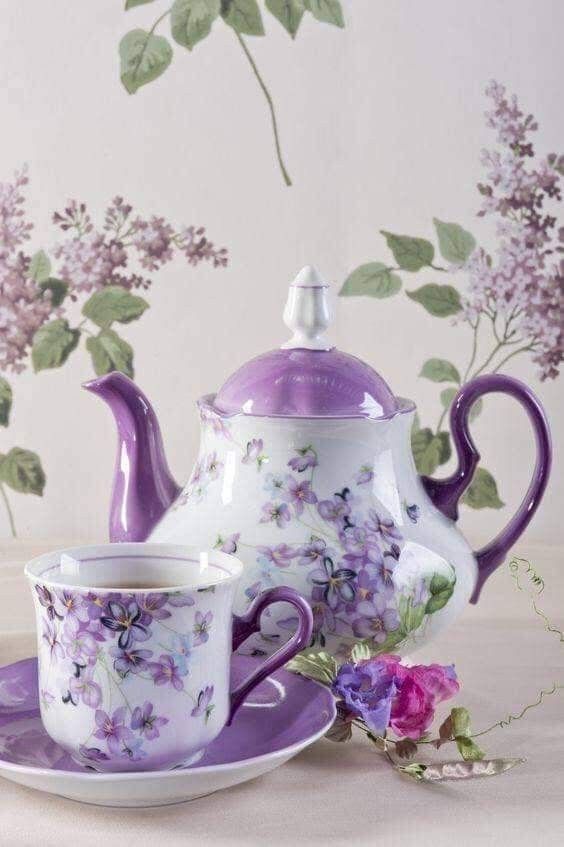 a tea set with purple flowers on the side and a saucer, cup and saucer