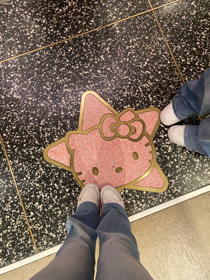 someone is standing on the floor with their feet in front of a hello kitty sticker