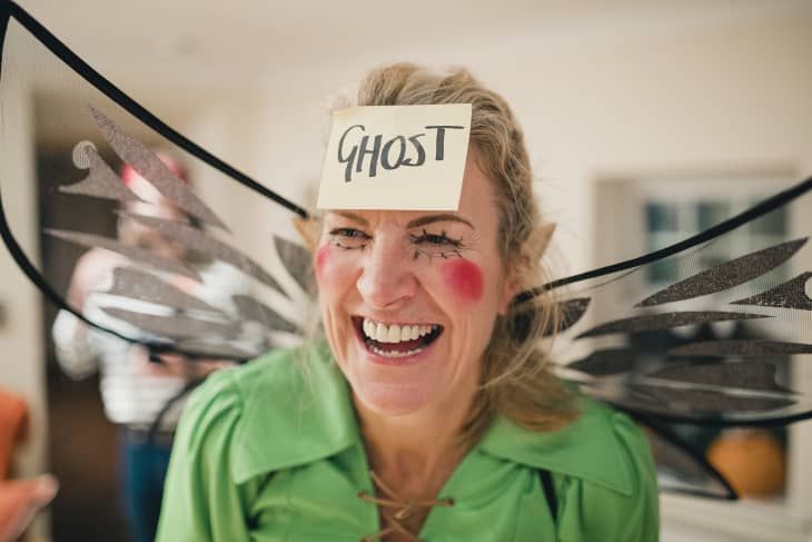 a woman with her face painted like a fairy holding scissors in front of her head