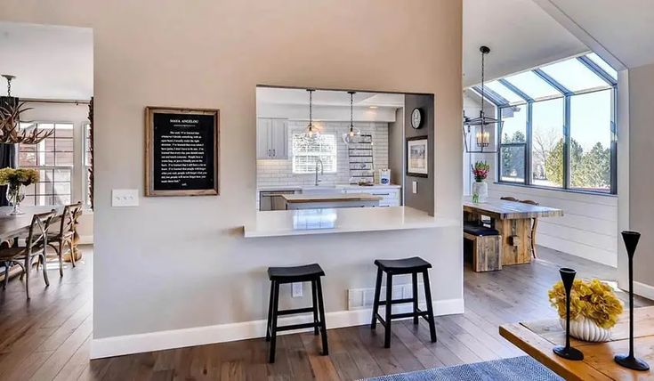 an open concept kitchen and dining room with hardwood floors, white walls, and large windows