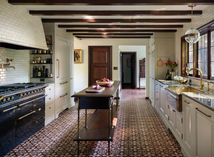 a kitchen with an oven, sink and stove top on the floor in front of two windows