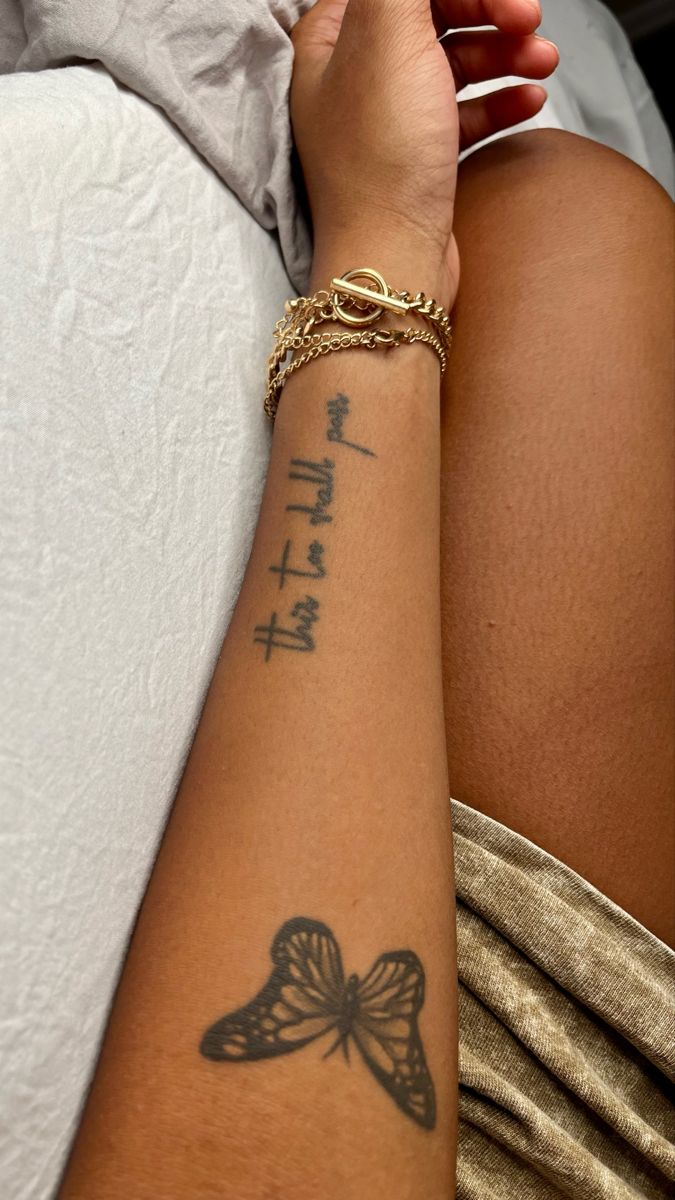 a woman's arm with a butterfly tattoo on it and chinese characters written across the arm