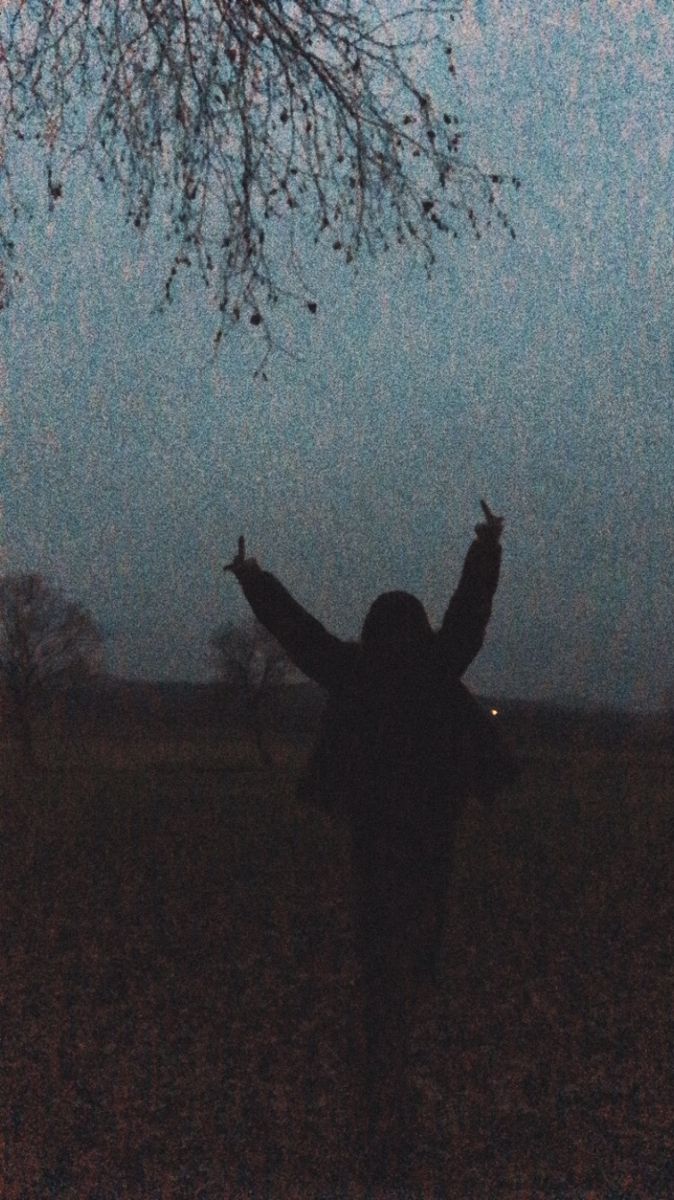 a person standing under a tree with their arms in the air