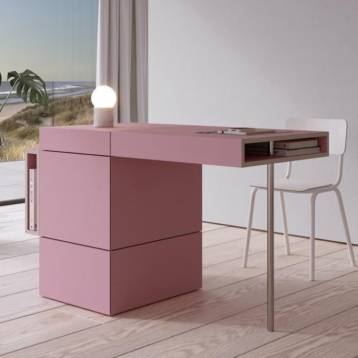 a pink desk in front of a window with a view of the beach and ocean