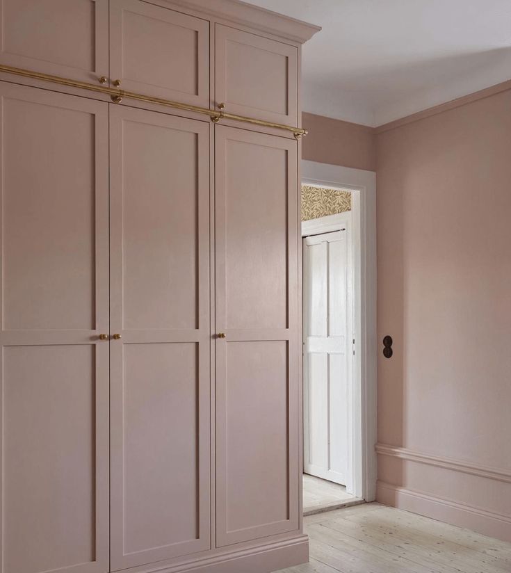 an empty room with pink painted walls and wooden flooring is pictured in this image