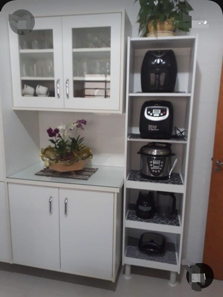 a kitchen with white cupboards and plants on the counter top in front of it