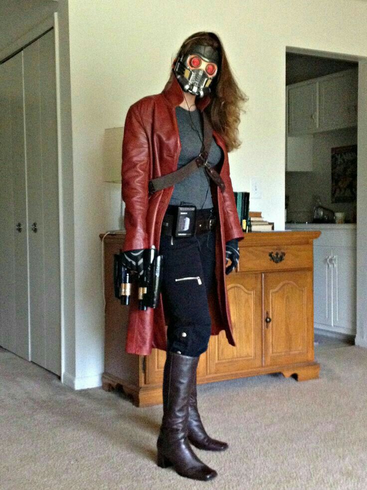 a woman wearing a red leather jacket and gas mask standing in a room with a dresser