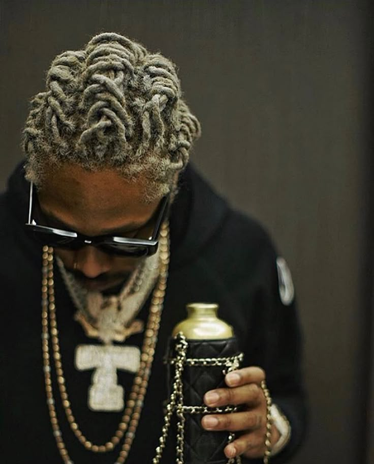 a man with dreadlocks is holding a beer and wearing a chain around his neck