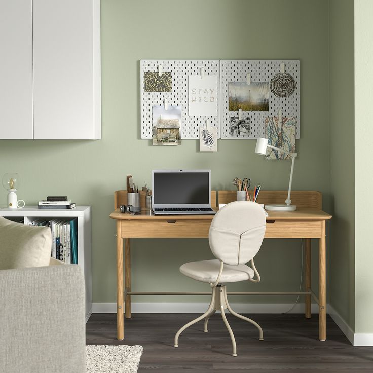 a desk with a laptop on top of it in front of a wall mounted cabinet