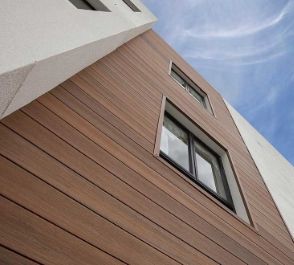 the side of a tall building with windows on it's sides and sky in the background