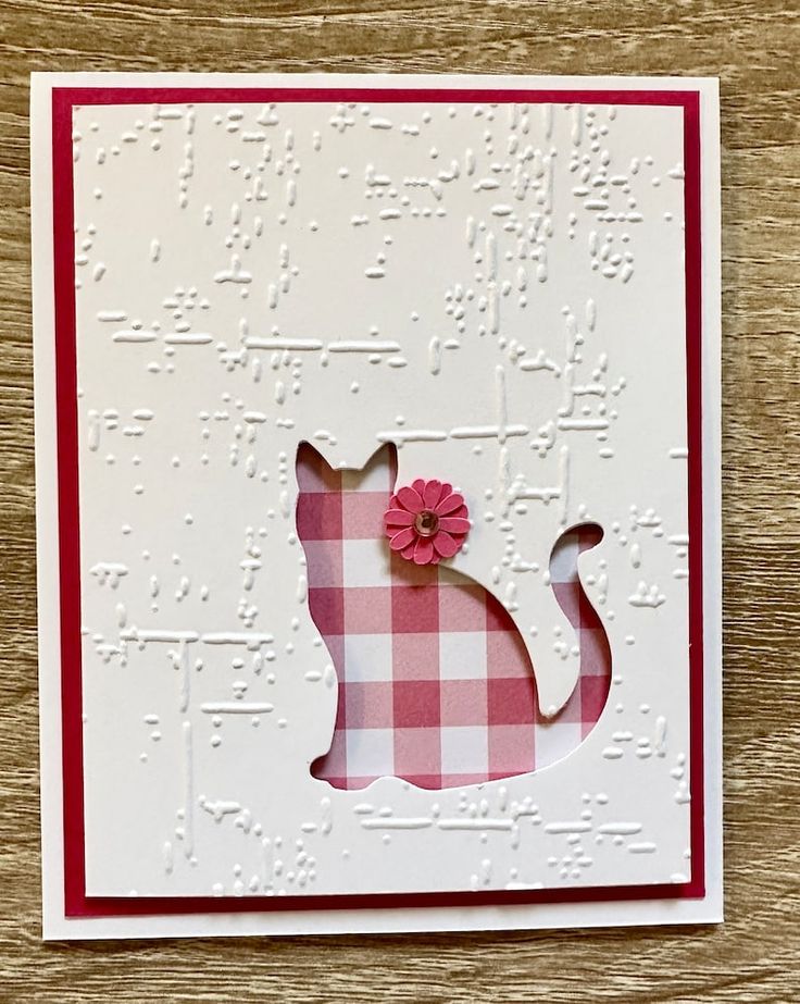 a pink and white card with a cat on it's side, which has a flower in the middle