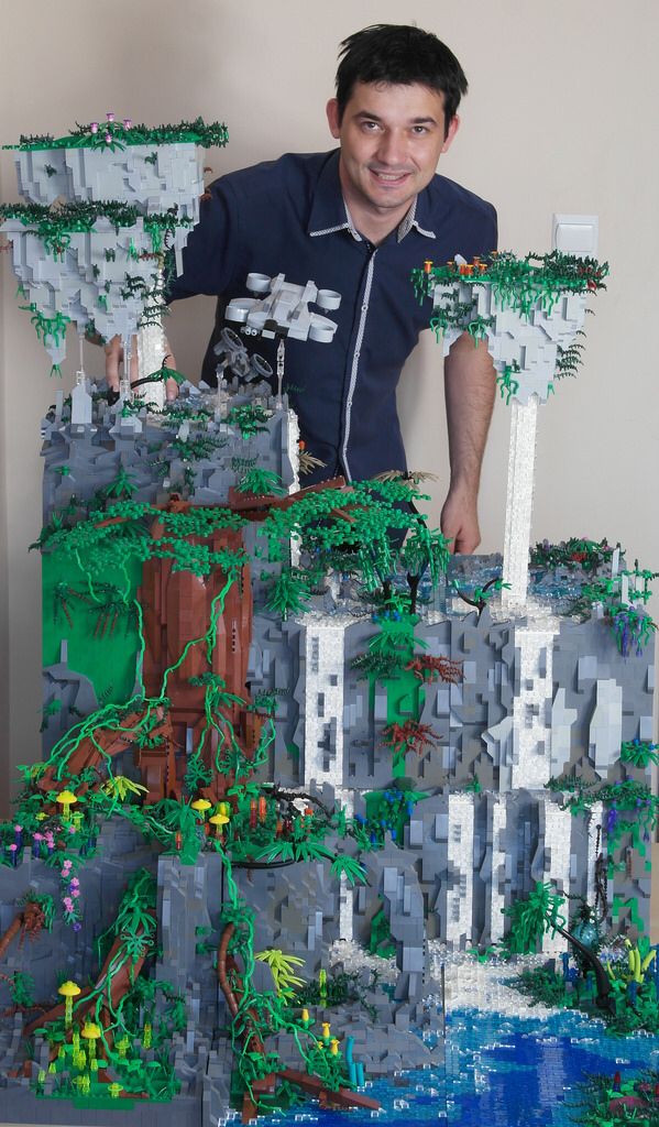 a man standing in front of a lego model of a city with trees and buildings