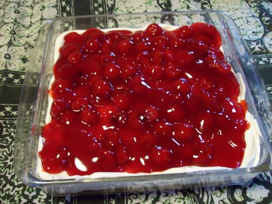 an uncooked dessert with cherries on top in a glass baking dish, ready to be baked