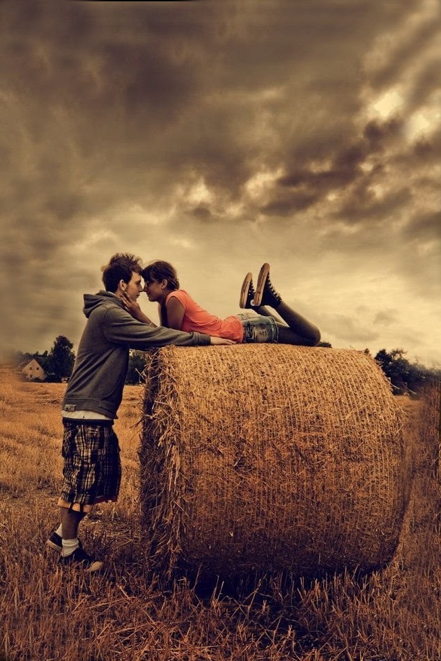 two people laying on hay bales kissing each other