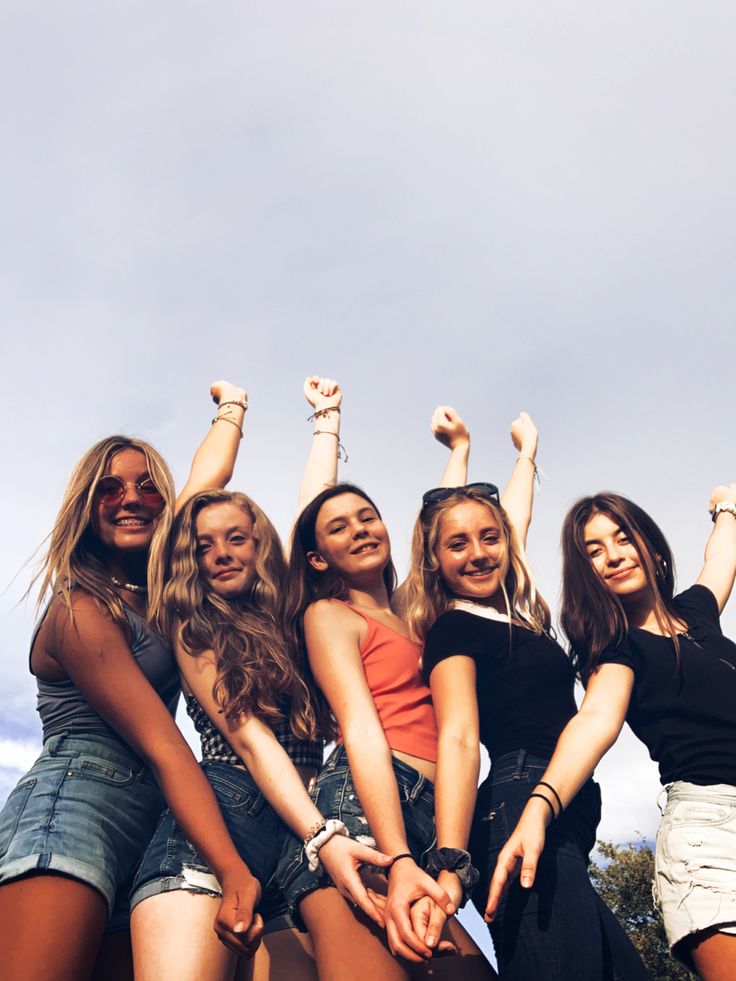 a group of young women standing next to each other with their arms in the air