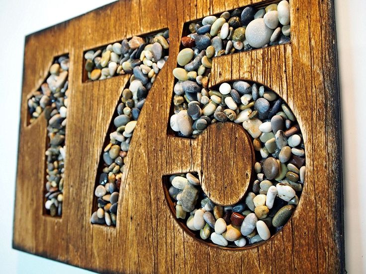 a wooden sign with rocks in the shape of number seventy five on it's side