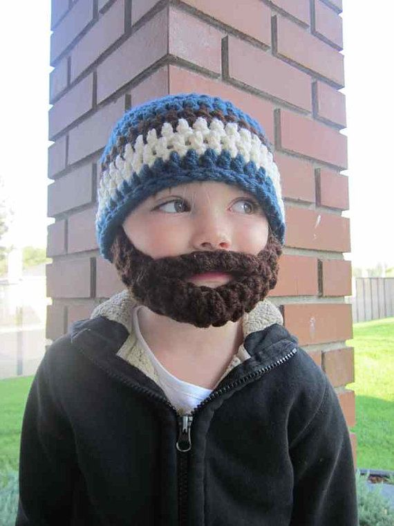 a young boy wearing a knitted hat with a beard and mustache standing in front of a brick building