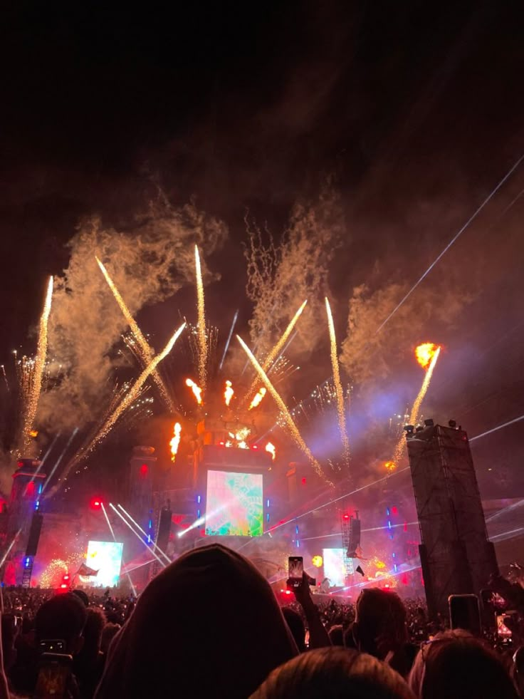 fireworks are lit up in the night sky at an outdoor concert