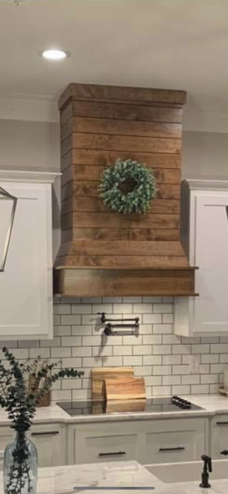 a kitchen with white cabinets and wooden stove hood