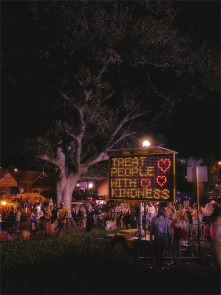 a large sign that is in the middle of a field with people standing around it