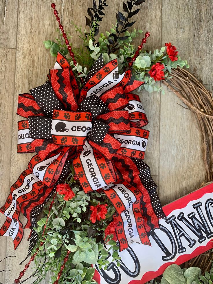 a red and black wreath with the words proud on it next to a couple of flowers