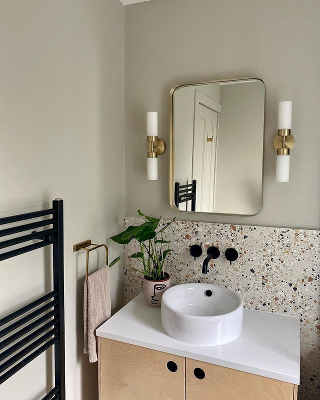 a white sink sitting under a bathroom mirror next to a radiator and towel rack