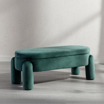 a green bench sitting on top of a hard wood floor next to a white wall