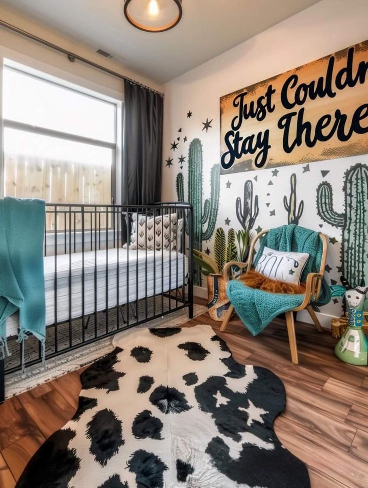 a baby's room with a cactus theme on the wall and a black metal crib