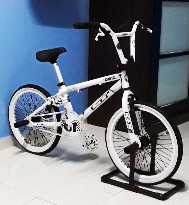 a white bicycle parked in front of a blue wall