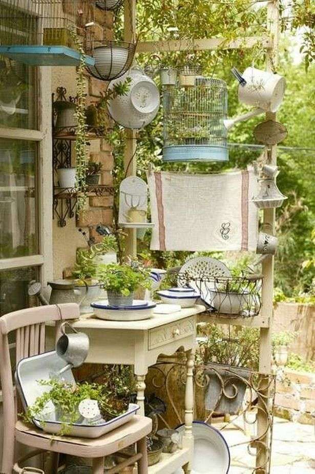 an outdoor table with chairs and plants on it in front of a window filled with birdcages