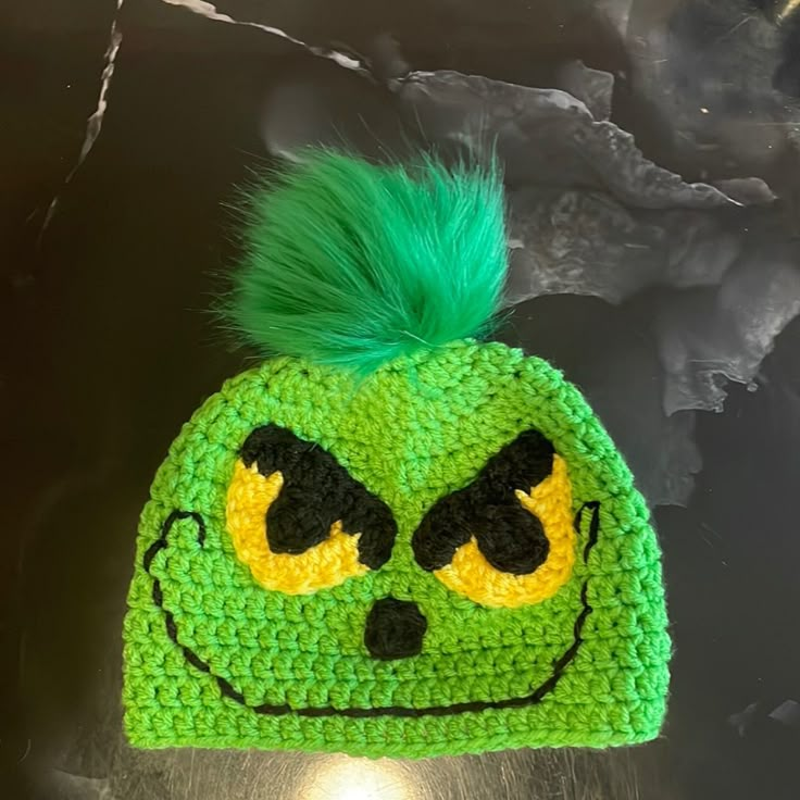 a crocheted hat with green hair and eyes