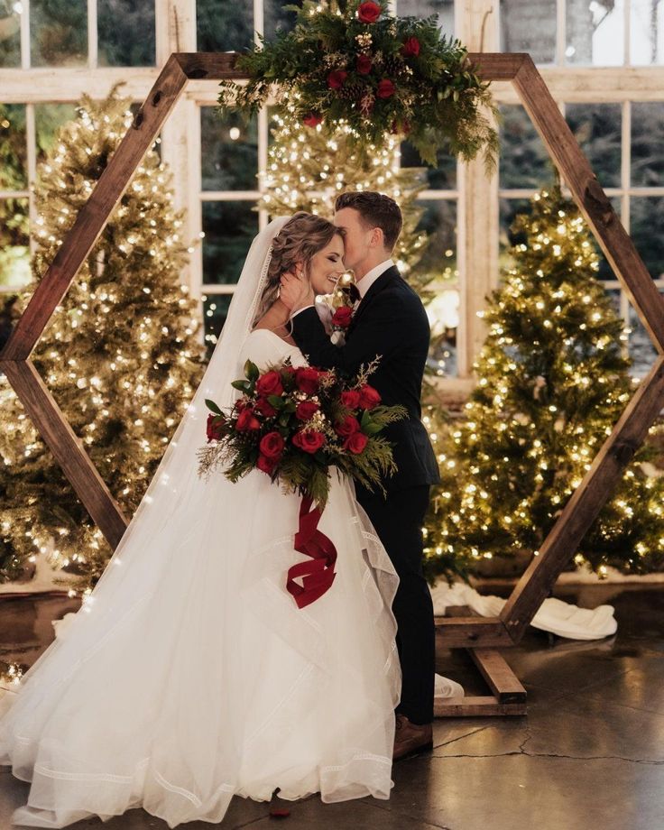 a bride and groom standing in front of christmas trees