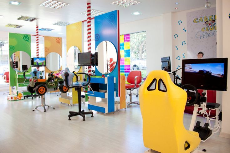 the interior of a children's hair salon with colorful chairs and mirrors on the walls