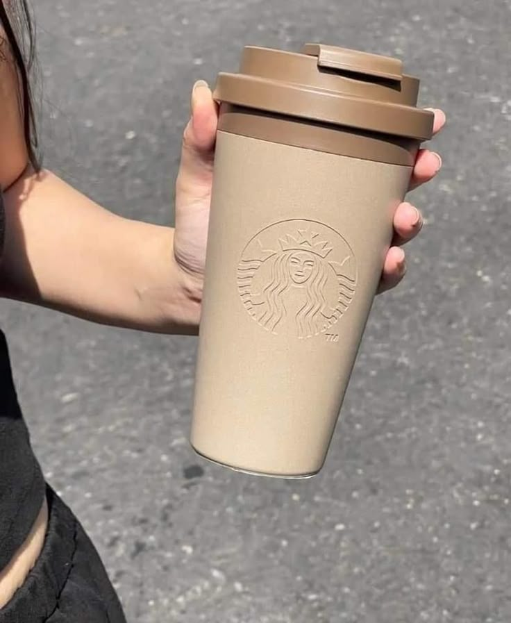 a woman holding a starbucks cup in her hand