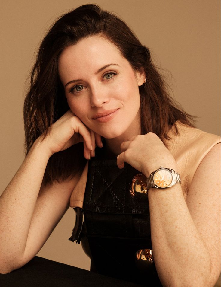 a woman sitting at a table with her hand on her chin and looking off to the side