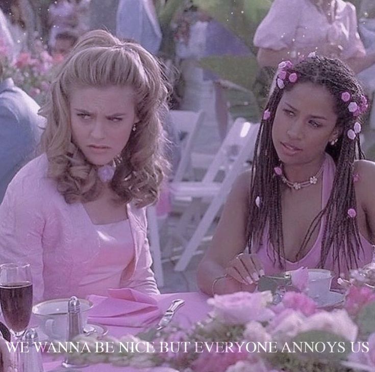 two women sitting at a table with pink flowers in their hair and one woman holding a glass of wine