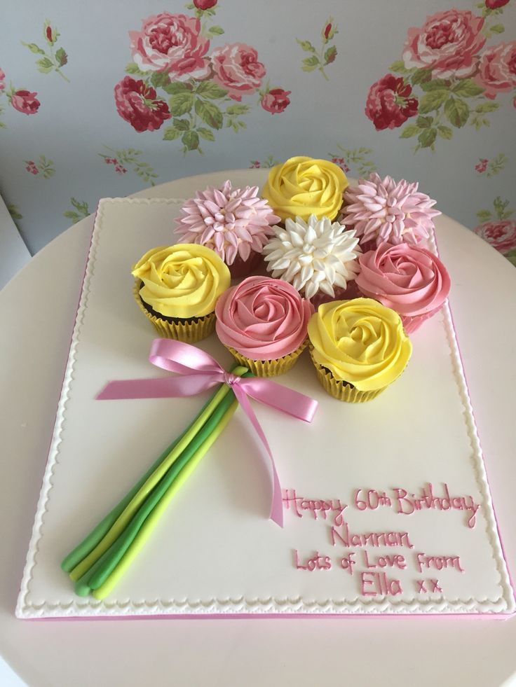 a birthday cake with cupcakes and flowers on it