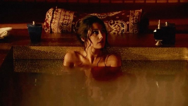 a woman sitting in a bathtub with her eyes closed