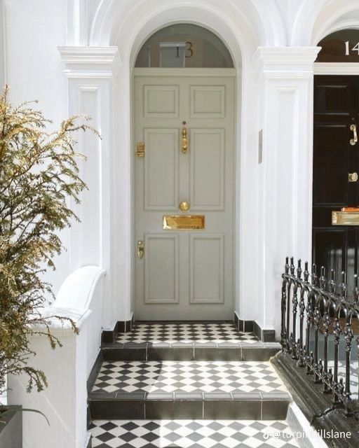 an entry way with black and white checkered flooring, gold hardware on the door