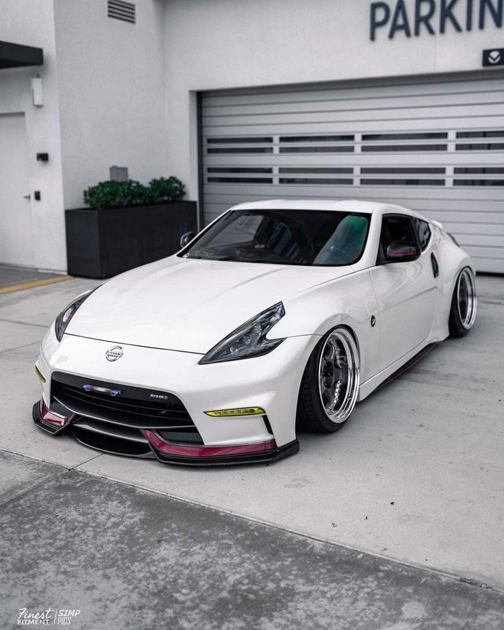 a white sports car parked in front of a garage