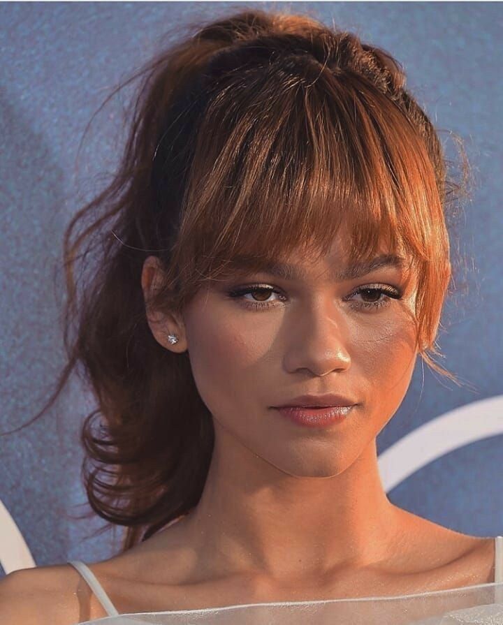 a close up of a person with freckles on her face and hair pulled back