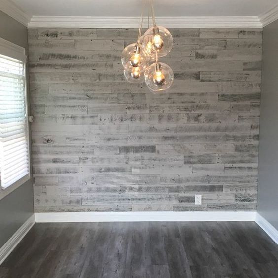 an empty living room with wood flooring and gray painted walls, chandelier hanging from the ceiling