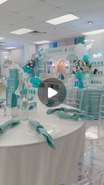 a white table topped with lots of chairs and tables covered in blue ribboned napkins